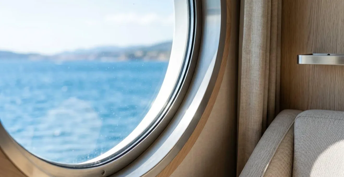 Nahaufnahme eines runden Bullauges in einer modernen Fährkabine mit unscharfem Blick auf das blaue Mittelmeer