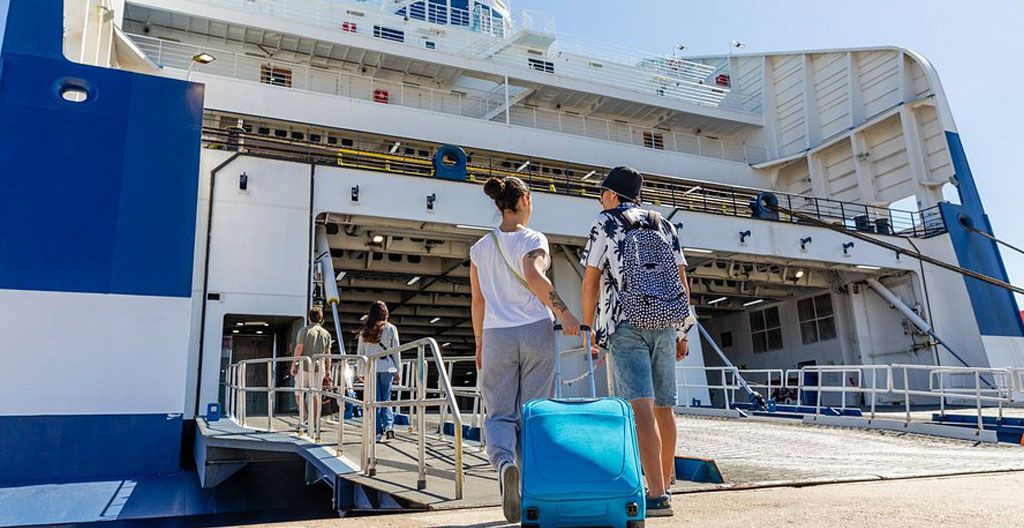 Weitwinkelaufnahme einer modernen europäischen Fährhafenanlage mit Fahrzeugeinfahrtsrampe und mehrsprachiger Beschilderung bei Tageslicht