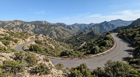 Serpentinenstraße windet sich durch die wilde Berglandschaft des sardischen Hinterlands unter strahlend blauem Himmel